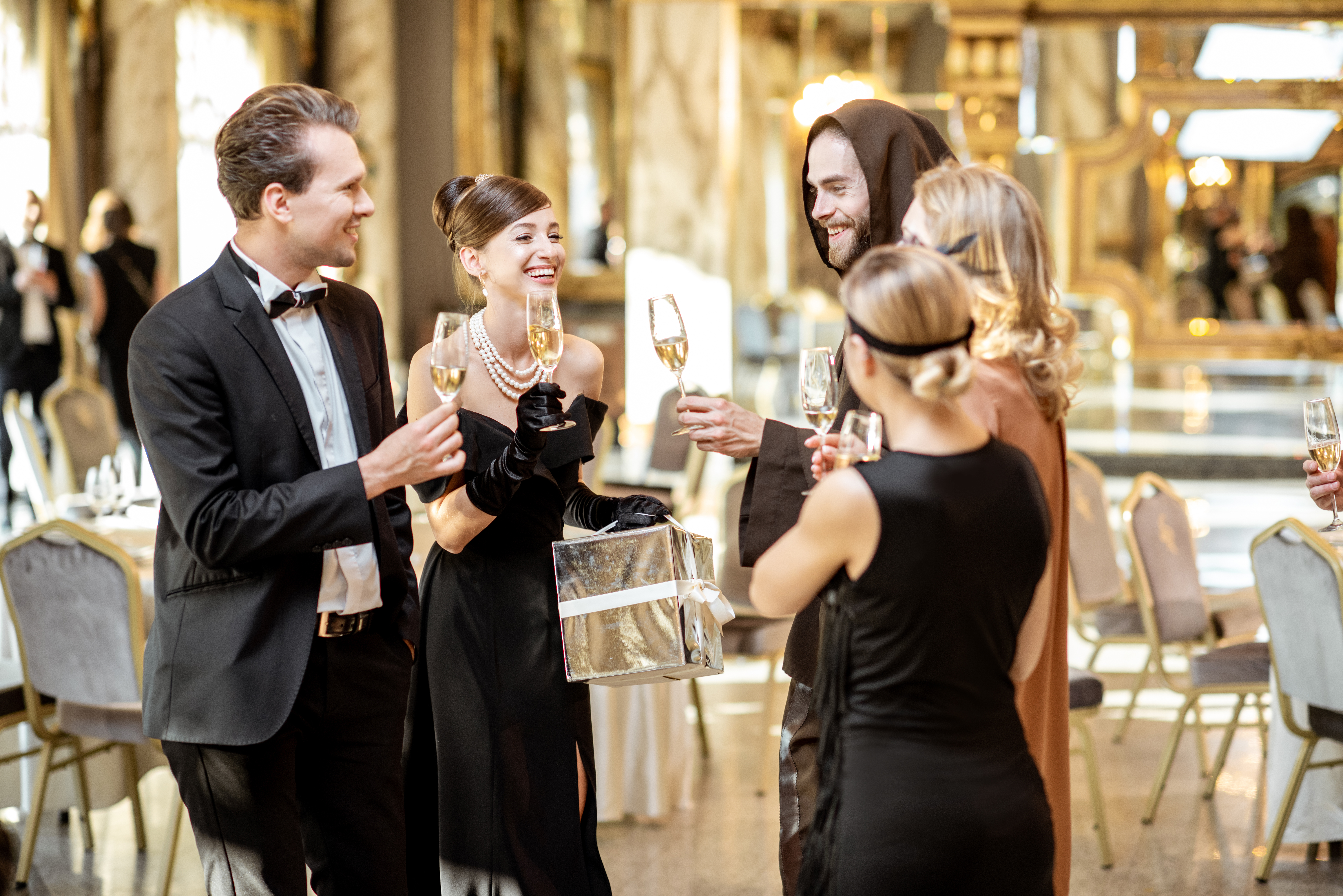 Group of elegant people well-dressed in retro styles celebrating New Year holiday, having fun together with wineglasses at the luxury restaurant hall